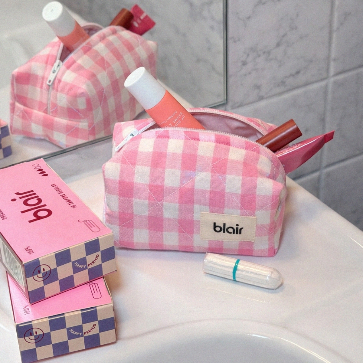 En rosa necessär från Blair för tamponger på ett vitt handfat med rosa Blair-förpackningar med tamponger vid sidan