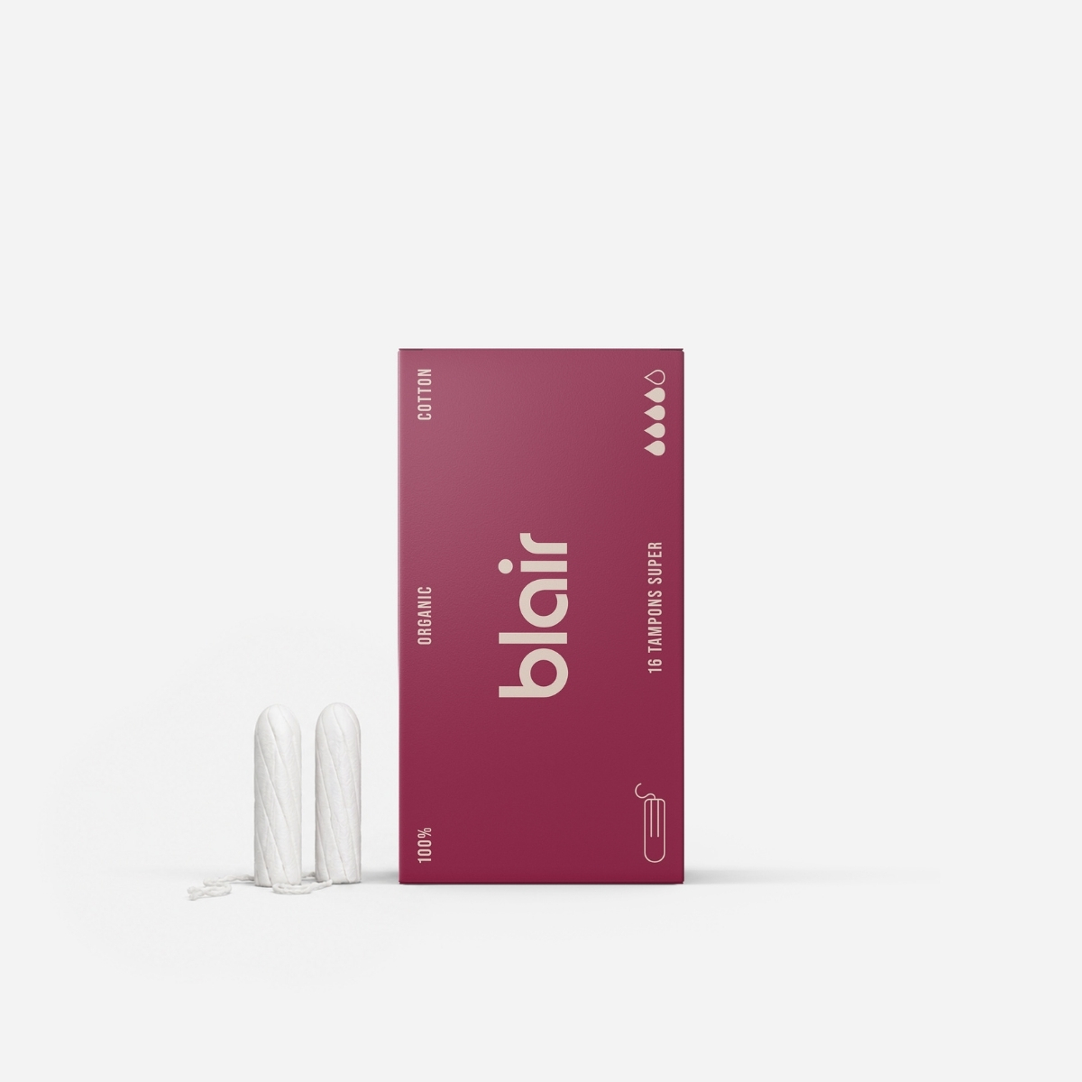 En röd Blair-förpackning med tamponger på en grå bakgrund med två tampponger i bomull bredvid