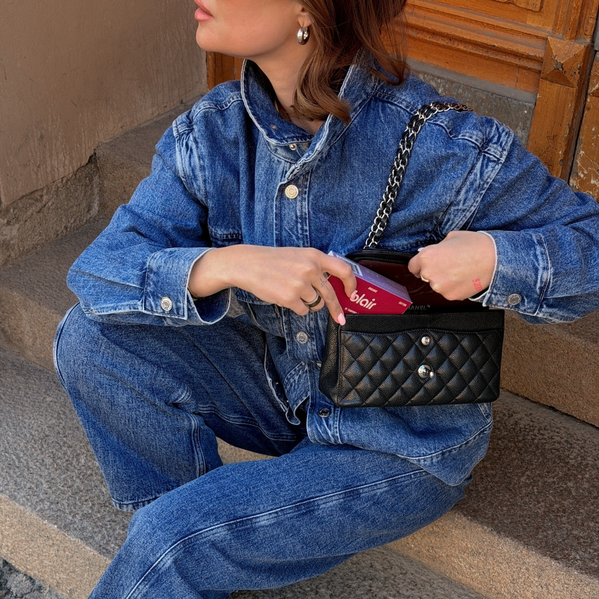 En tjej i ett denim set som håller i ett vinrött paket med blair-tamponger