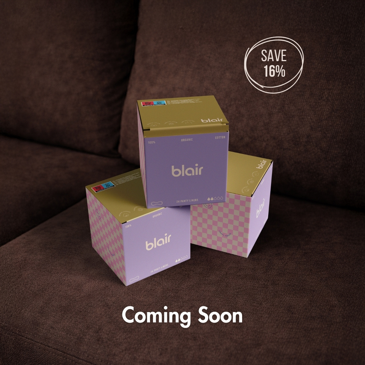 Tre förpackningar med Blair trosskydd, i rosa och lila rutigt mönster på en brun soffa, staplade på varandra med texten Coming Soon skrivet på bilden