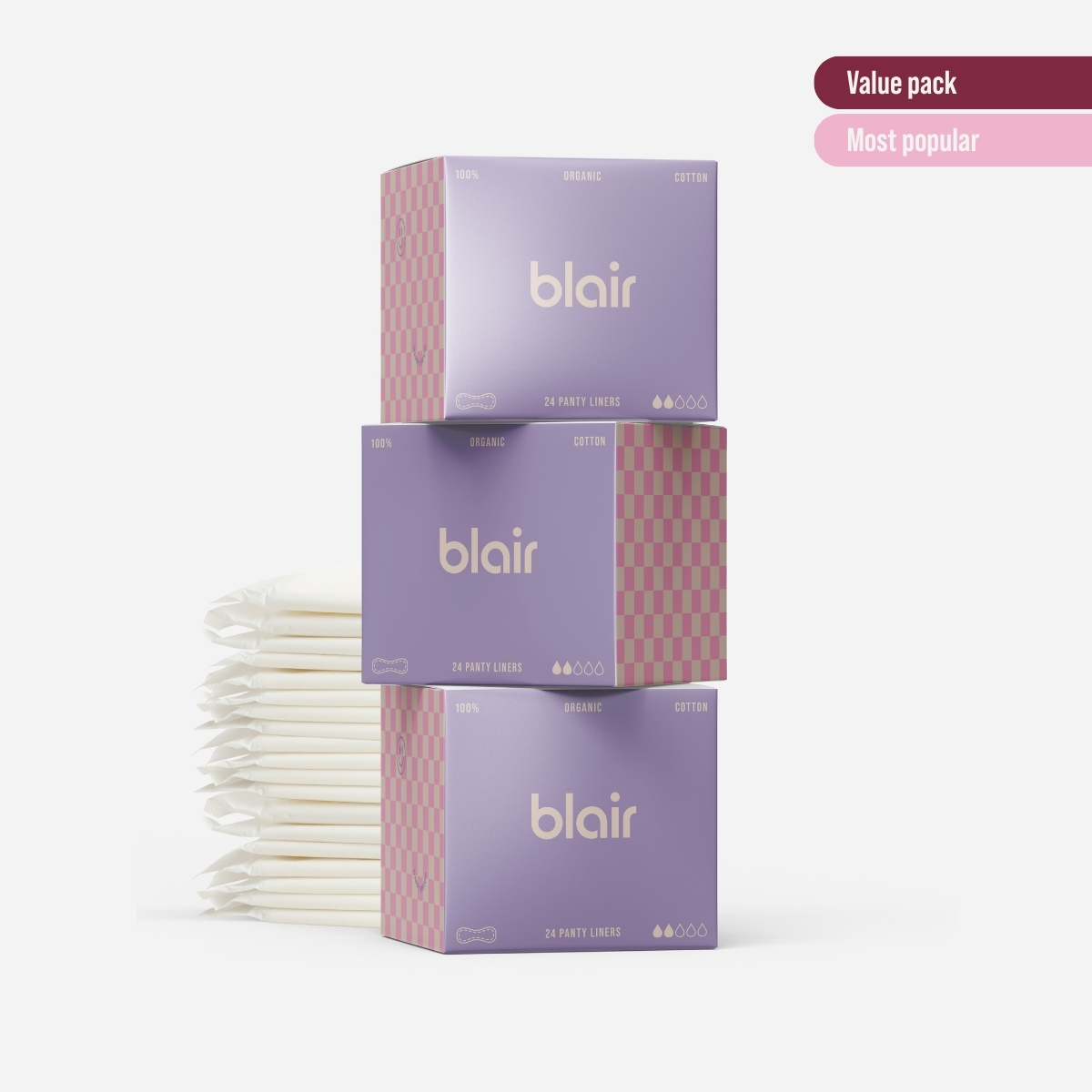Tre Blair-förpackningar med bindor, trosskydd och tamponger på en grå bakgrund med vikta trosskydd vid sidan